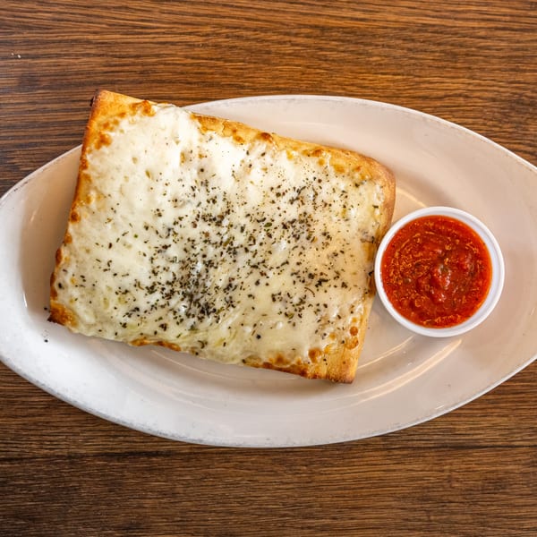 Cheesy bread with herbs and a side of marinara sauce on a white plate.